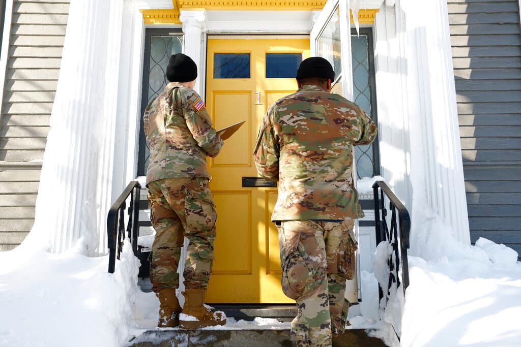 Dos elementos de la Guardia Nacional visitan una casa para ver cómo se encuentran sus ocupantes tras la tormenta invernal, el miércoles 28 de diciembre de 2022, en Buffalo, Nueva York.
