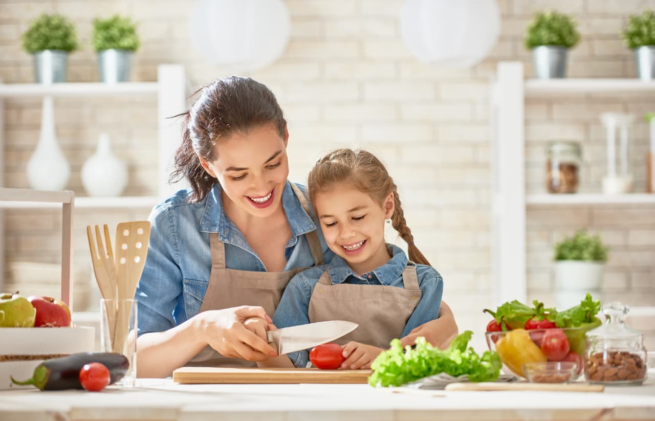 Healthy food at home. Happy family in the kitchen. Mother and child daughter are preparing the vegetables and fruit.