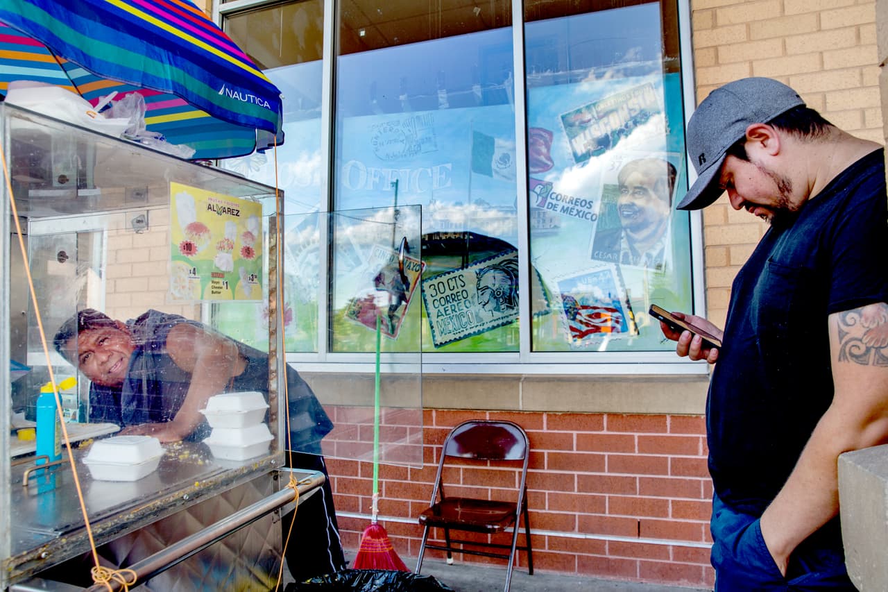 Un vendedor de elotes atiende a clientes en su pequeño negocio ambulante.