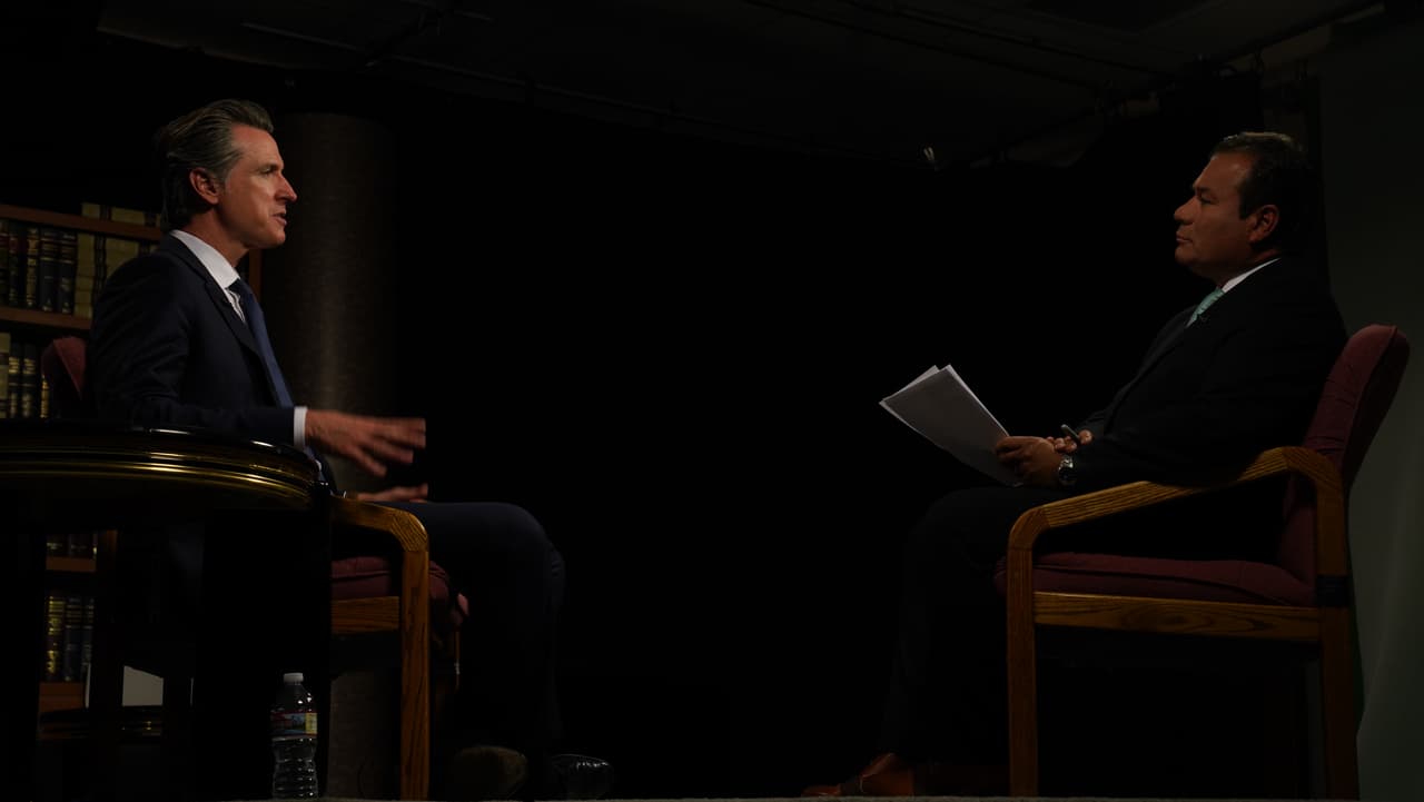 El gobernador Gavin Newsom (izquierda) habla con Jairo Díaz-Pedraza sobre sus planes para implementar políticas migratorias que se diferencian a las de la administración de Donald Trump.