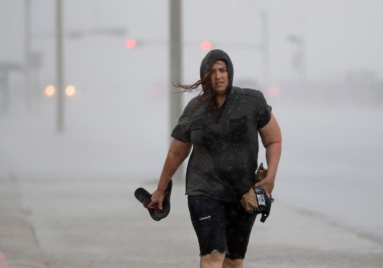 Una mujer camina bajo la lluvia en la vía que bordea el mar en la isla de Galveston, al sur de Houston, Texas.