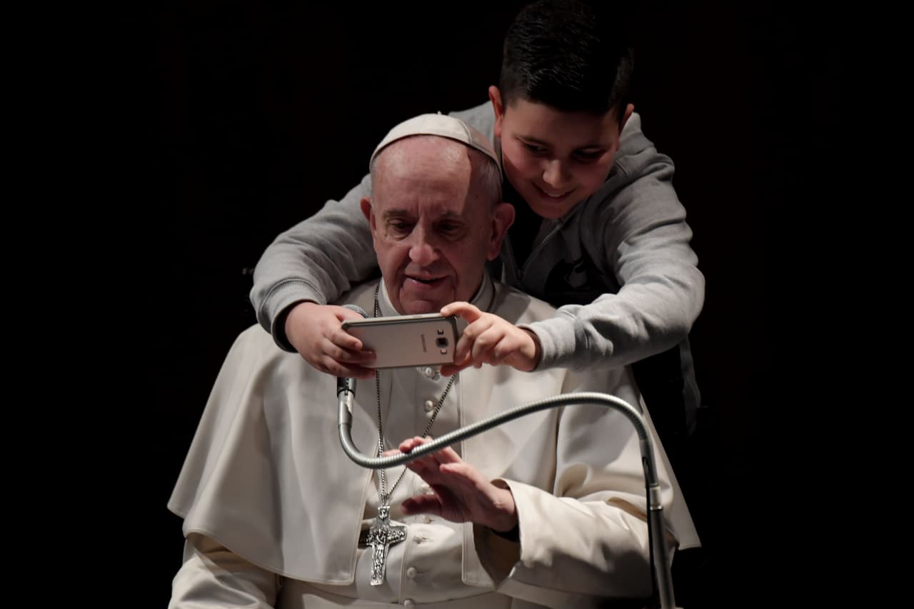 <b>Selfie Papal, 2017.</b> El argentino Jorge Bergoglio, el papa Francisco, aparta el micrófono para ayudar a un pequeño seguidor a tomar un buen selfie en una iglesia de Roma.
