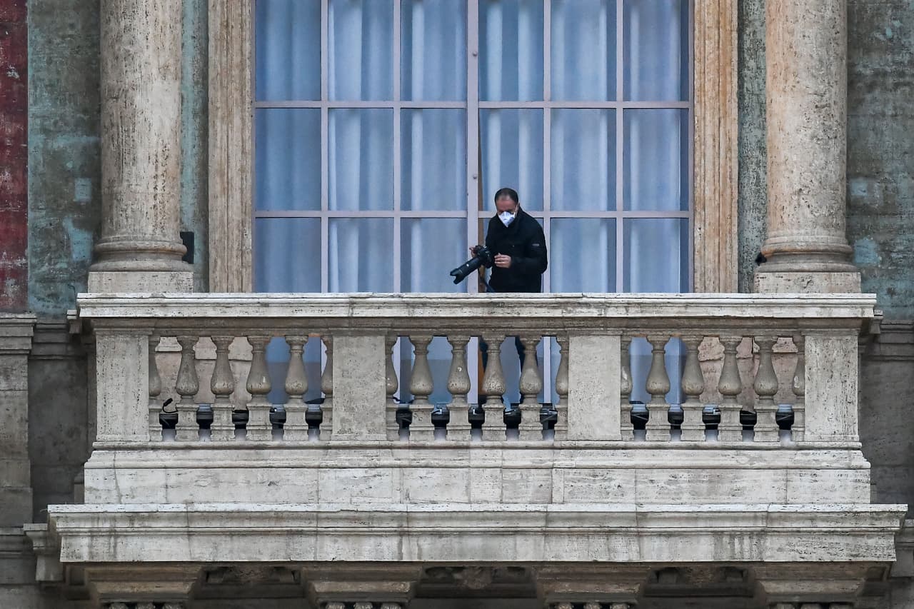 Un fotógrafo oficial del Vaticano con una máscara facial registra el inusual evento desde un balcón de la basílica de San Pedro, antes de que el Papa presidiera un momento de oración frente de la fachada de la basílica.