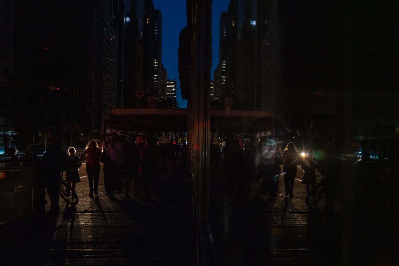 NUEVA YORK, NY - 13 DE JULIO: Una mujer se sienta dentro de un Duane Read en la calle 57 tratando de usar su teléfono celular durante el apagón. (Foto de David Dee Delgado/Getty Images)