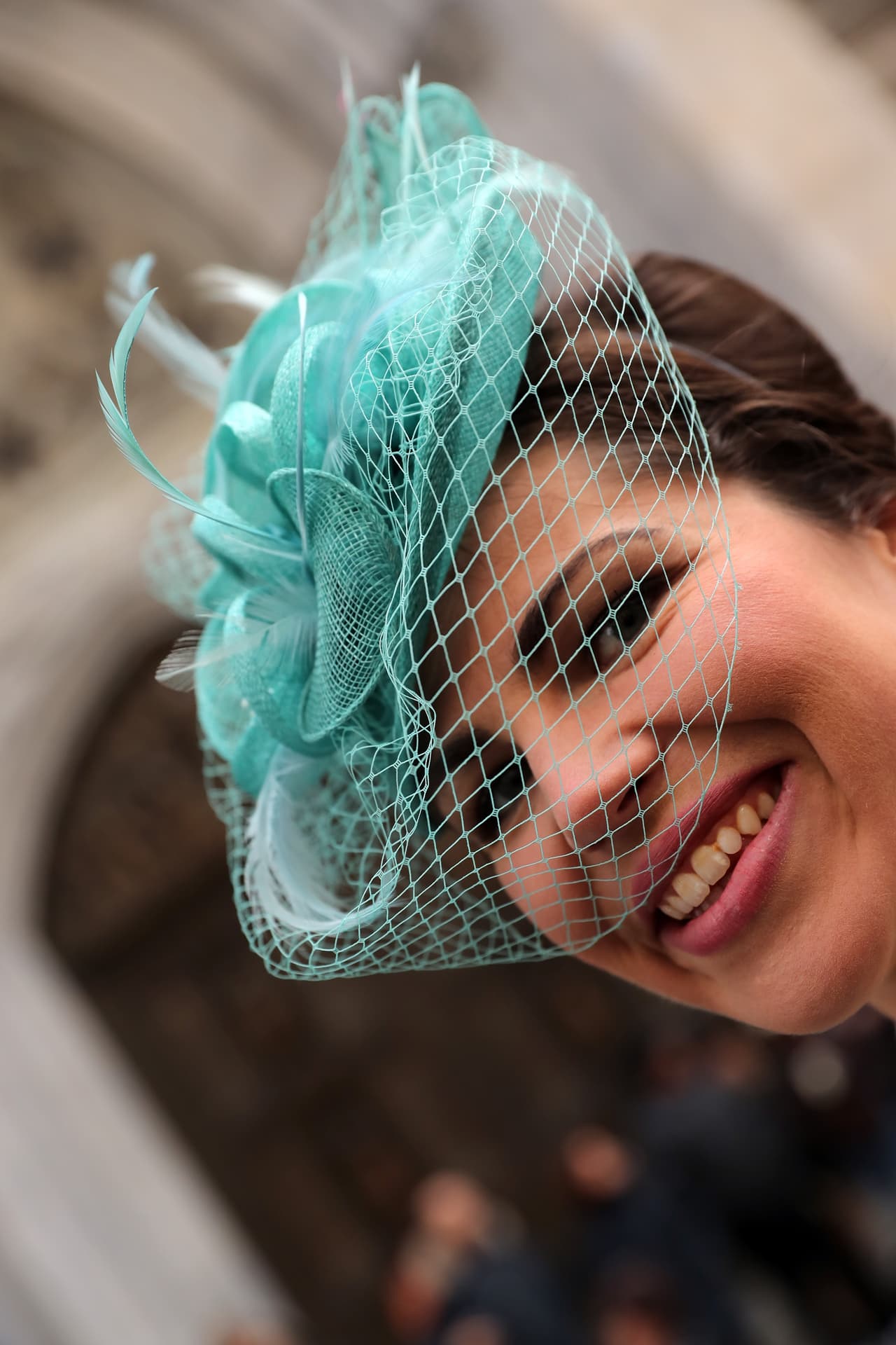 Una mujer sonríe y muestra su sombrero de tule