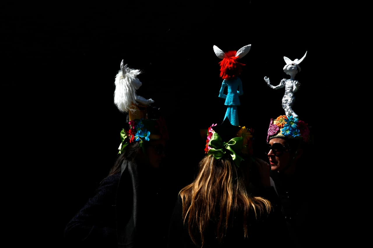 Tres personas caminan con sombreros de los que sobresale un conejo de Pascua sobre su cabeza