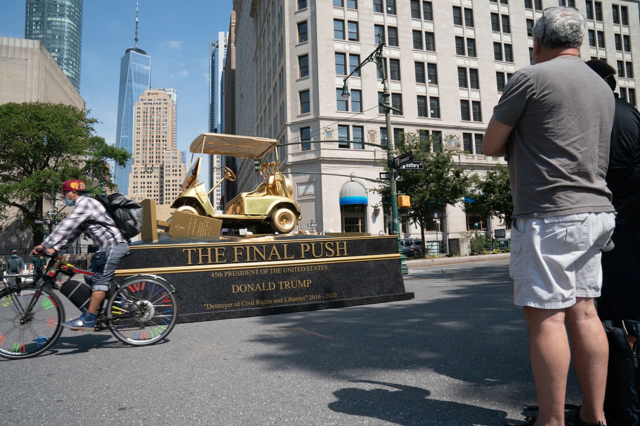 La estatua satírica muestra a Trump en el carro sosteniendo su palo de golf hacia el horizonte...