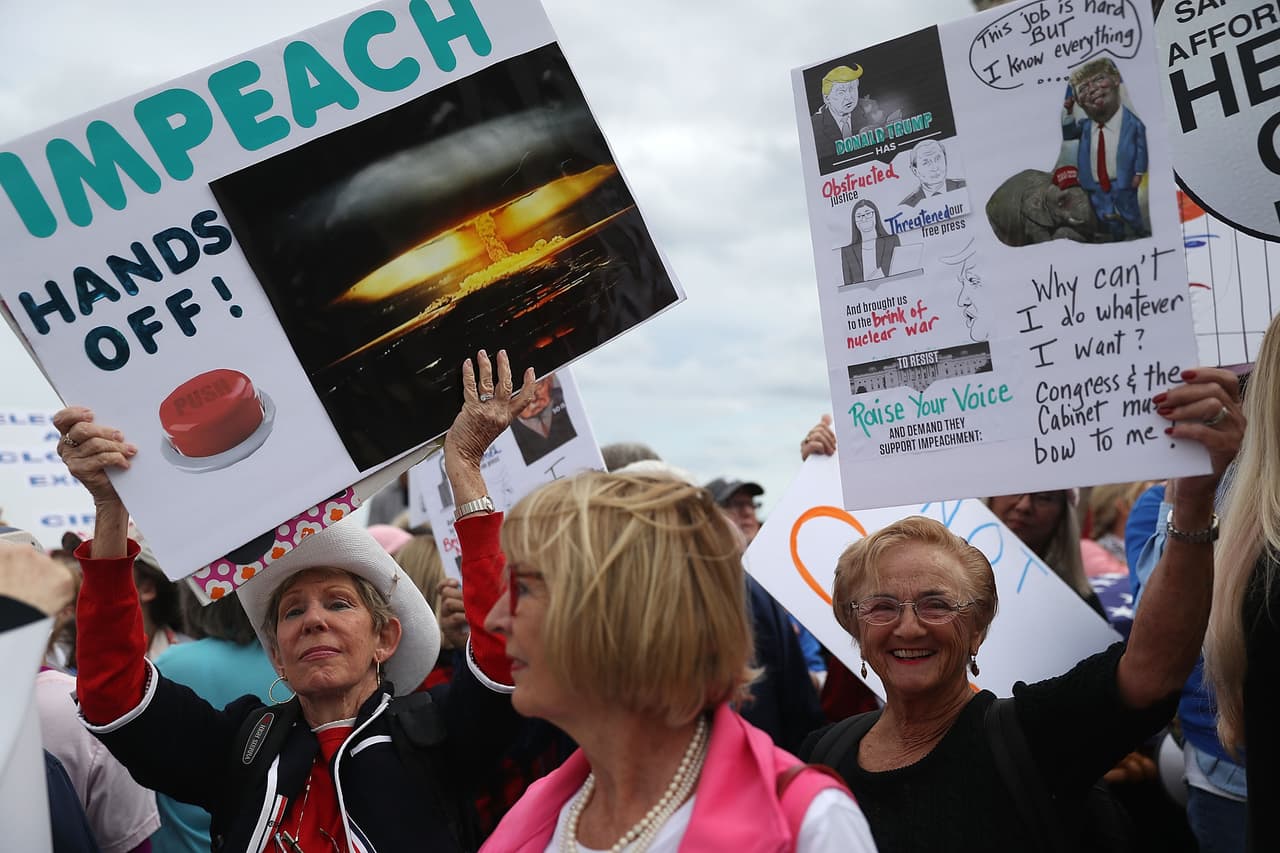 Decenas de personas de mujeres llegaron hasta Mar-a-lago para protestar contra Donald Trump. Llevan carteles donde piden que sea destituido.