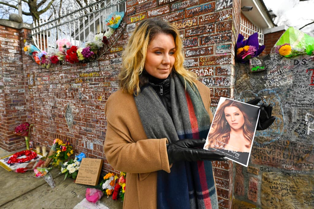 En la imagen, Chelsa Brinkman, una de las asistentes, se encuentra fuera del muro de piedra que bordea Graceland. Ella dejó un ramo de flores para Presley.