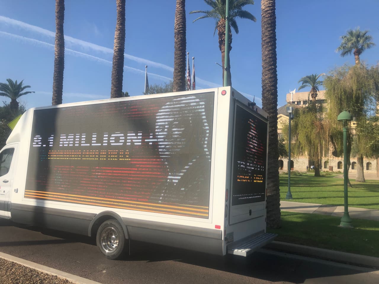 Un camión que es una valla publicitaria electrónica estacionado frente el Capitolio Estatal en Phoenix expresa su rechazo a la visita de Donald Trump al estado.