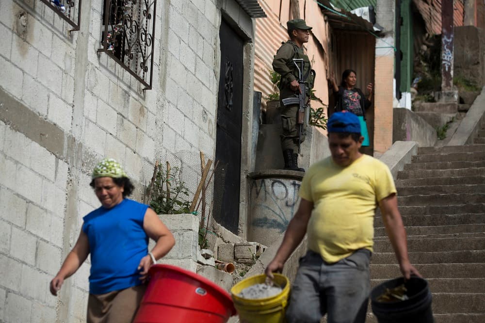 Vecinos cargando cubos vacíos de agua en el barrio de La Comuna 2, en Ciudad de Guatemala,