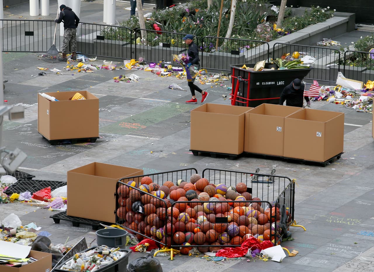 Trabajadores retiran miles de artículos dejados como ofrenda para Kobe Bryant en la Plaza X-Box, frente al Staples Center de Los Ángeles, el lunes 3 de febrero de 2020 (AP Foto/Reed Saxon)