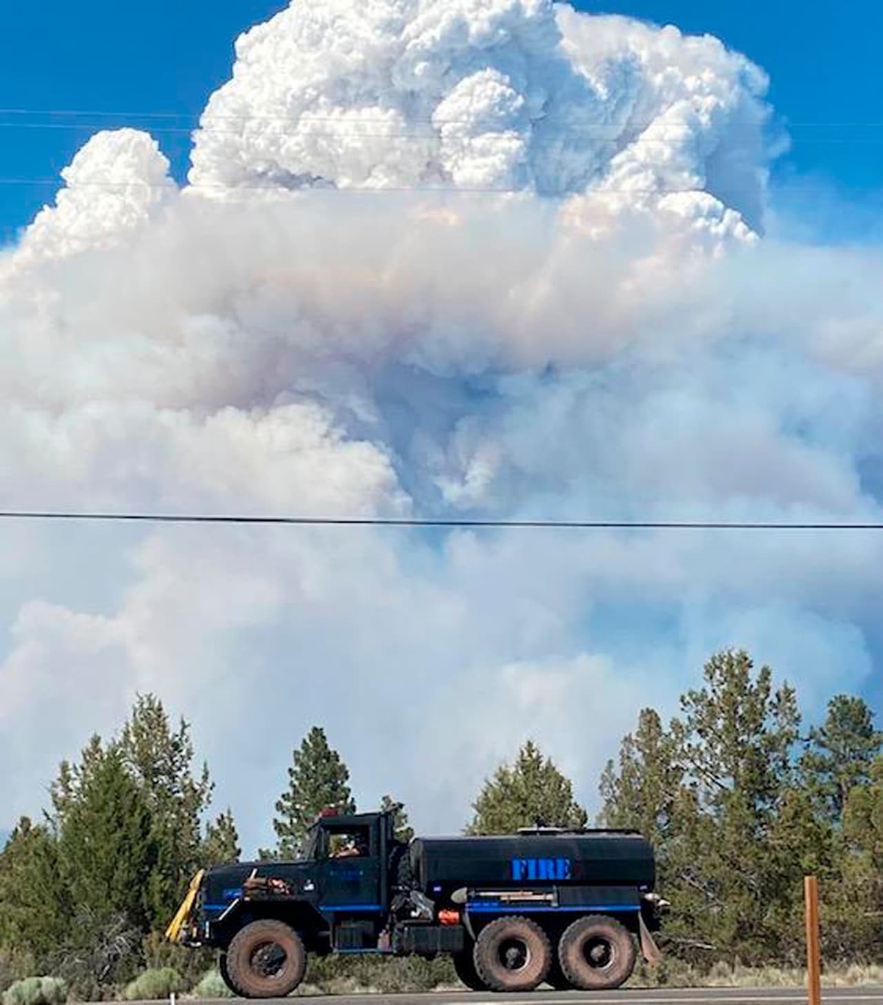 En esta foto proporcionada por el Bootleg Fire Incident Command, columnas de humo del 
<i>Bootleg Fire</i> se elevan detrás de una pipa de agua en el sur de Oregon el viernes 16 de julio de 2021. Los bomberos intentaron controlar el 
<a href="https://www.univision.com/temas/incendios">incendio</a> registrado en el sureste del estado, que se extiende millas por día. en condiciones de viento, uno de los numerosos incendios forestales en el oeste de Estados Unidos que están agotando los recursos.