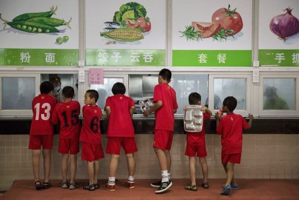 Aquí los niños hacen fila para recibir sus alimentos. Arriba una tabla nutrimental que deben seguir.