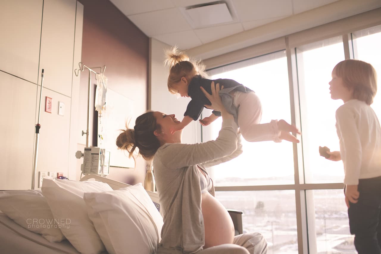 La madre en esta foto tenía a sus dos primeros hijos correteando por el cuarto mientras se encontraba en las primera etapas de labor de parto. Poco antes de que se la lleven a casa, la bebé se trepa a la cama para estar con su madre.