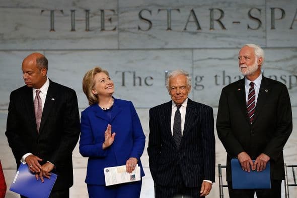 Hillary Clinton saluda a los espectadores durante una ceremonia de naturalización con Ralph Lauren, la secretaria de Seguridad Nacional, Jeh Johnson y el secretario del Smithsonian Wayne Clough.