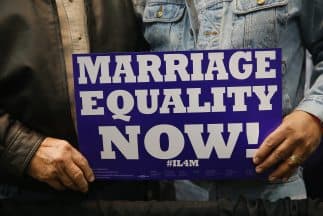 Una pareja sostiene un cartel a favor del matrimonio igualitario. 