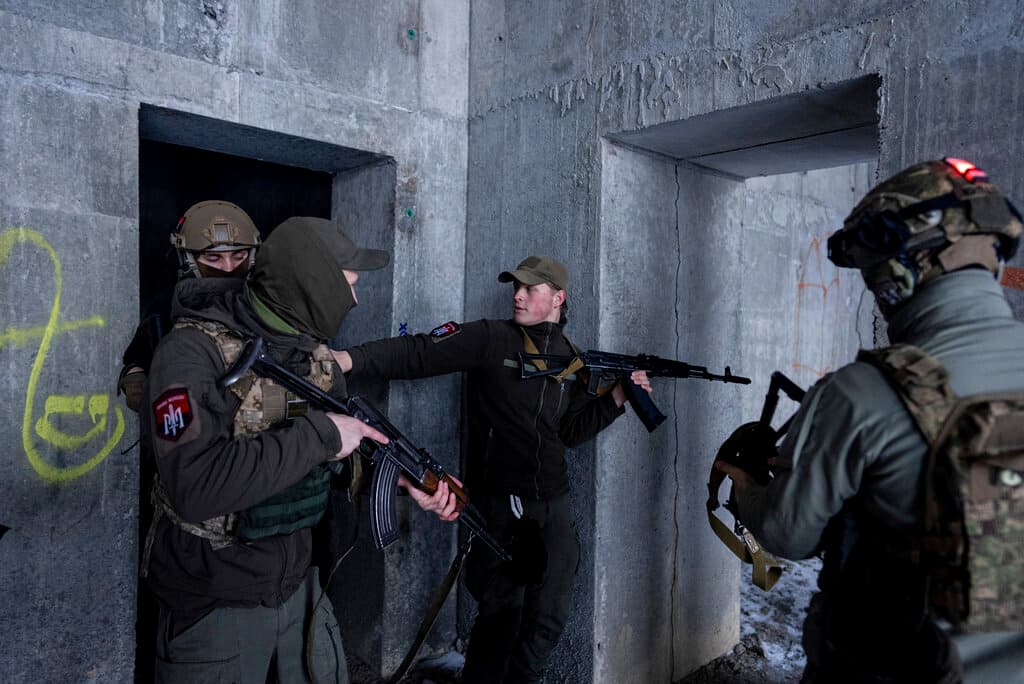 Un miembro de un grupo ucraniano de extrema derecha que se identificó con el nombre de guerra Pulsar, en el centro, discute las tácticas con sus compañeros durante un entrenamiento en Kharkiv, Ucrania. El grupo de jóvenes nacionalistas se reúne semanalmente en una obra abandonada, enmascarados y vestidos de negro mientras practican maniobras.