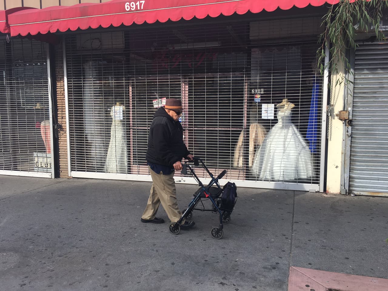 Un anciano camina frente a una tienda de ropa cerrada en el bulevar Pacific de la ciudad de Huntington Park, California.