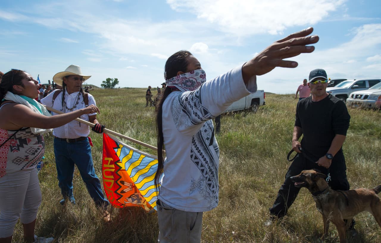 Un activista indígena alza sus brazos mientras él y los demás manifestantes son amenazados por guardias de seguridad privada y sus perros en el sitio de construcción del DAPL. Los nativos temen que podría contaminar sus aguas.