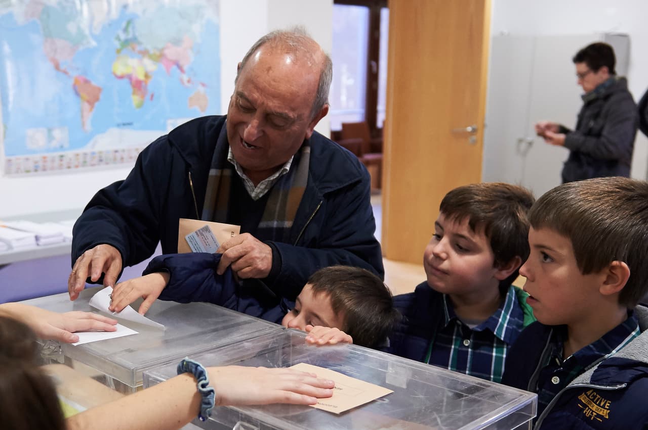 Un hombre vota con sus nietos.