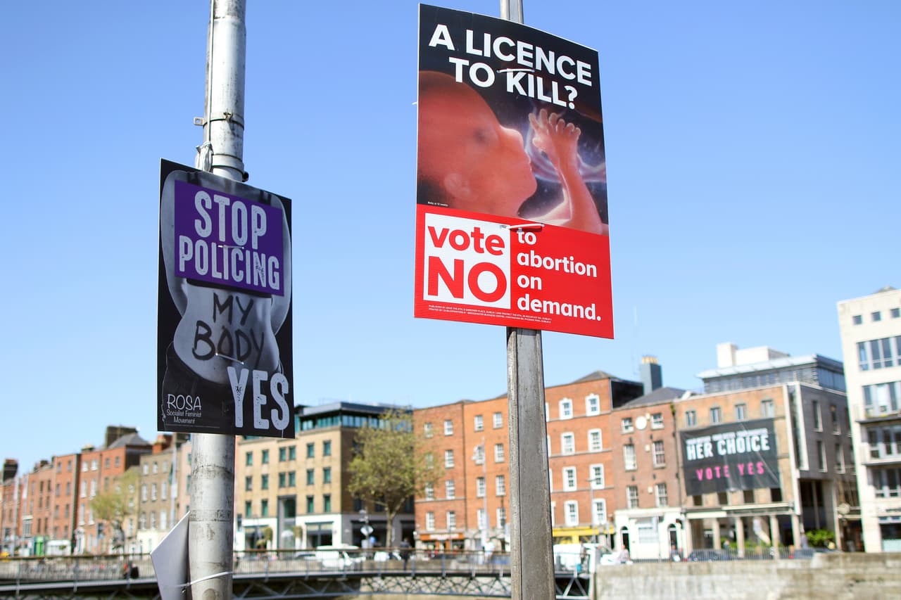 En esta fotografía se muestran carteles a favor y contra el aborto colgados en farolas, en Dublín.