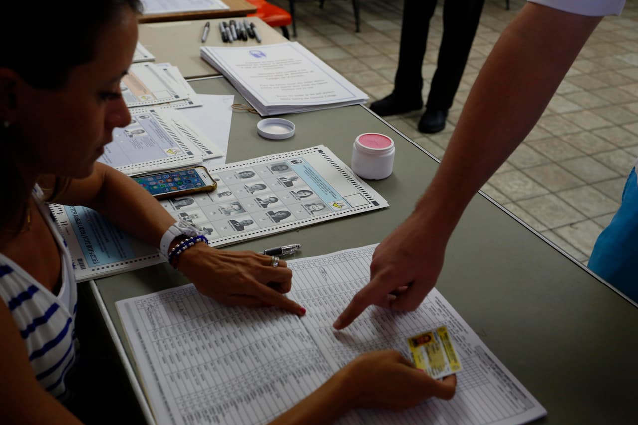 Verifica bien 
<a href="http://consulta.ceepur.org/" target="_blank"><b>dónde te toca votar</b></a>. Una vez llegues a tu colegio asignado, el funcionario en la puerta verificará tus dedos para ver que no estén entintados de un voto previo. Una vez verifiquen esto, te registras en la mesa con tu tarjeta electoral y firmas.