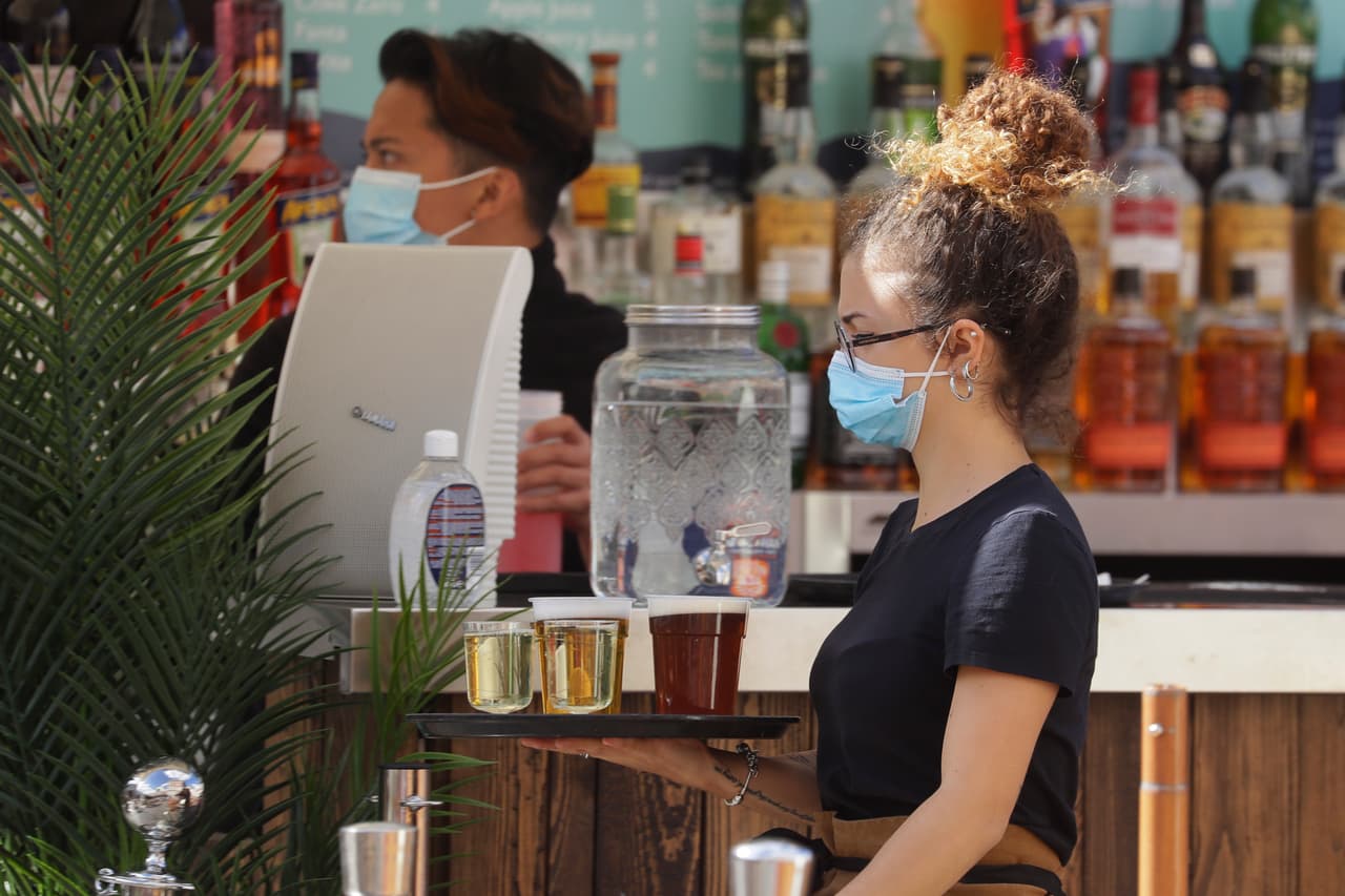 Personal atiende a clientes en un bar al aire libre en Londres, el jueves 24 de septiembre de 2020, después de que el primer ministro británico Boris Johnson anunciara una serie de nuevas restricciones para frenar la propagación del coronavirus en Inglaterra.