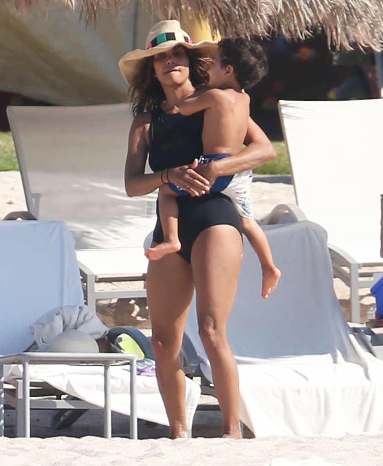 Se protegió del sol con un sombrero mientras cargaba a su pequeñín.