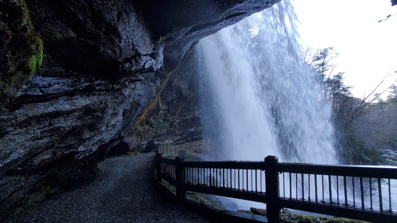 Las cascadas altas de 75 pies en el Bosque Nacional Nantahala fluyen sobre un acantilado, lo que permite caminar detrás de las cataratas y mantenerse seco (de ahí el nombre).