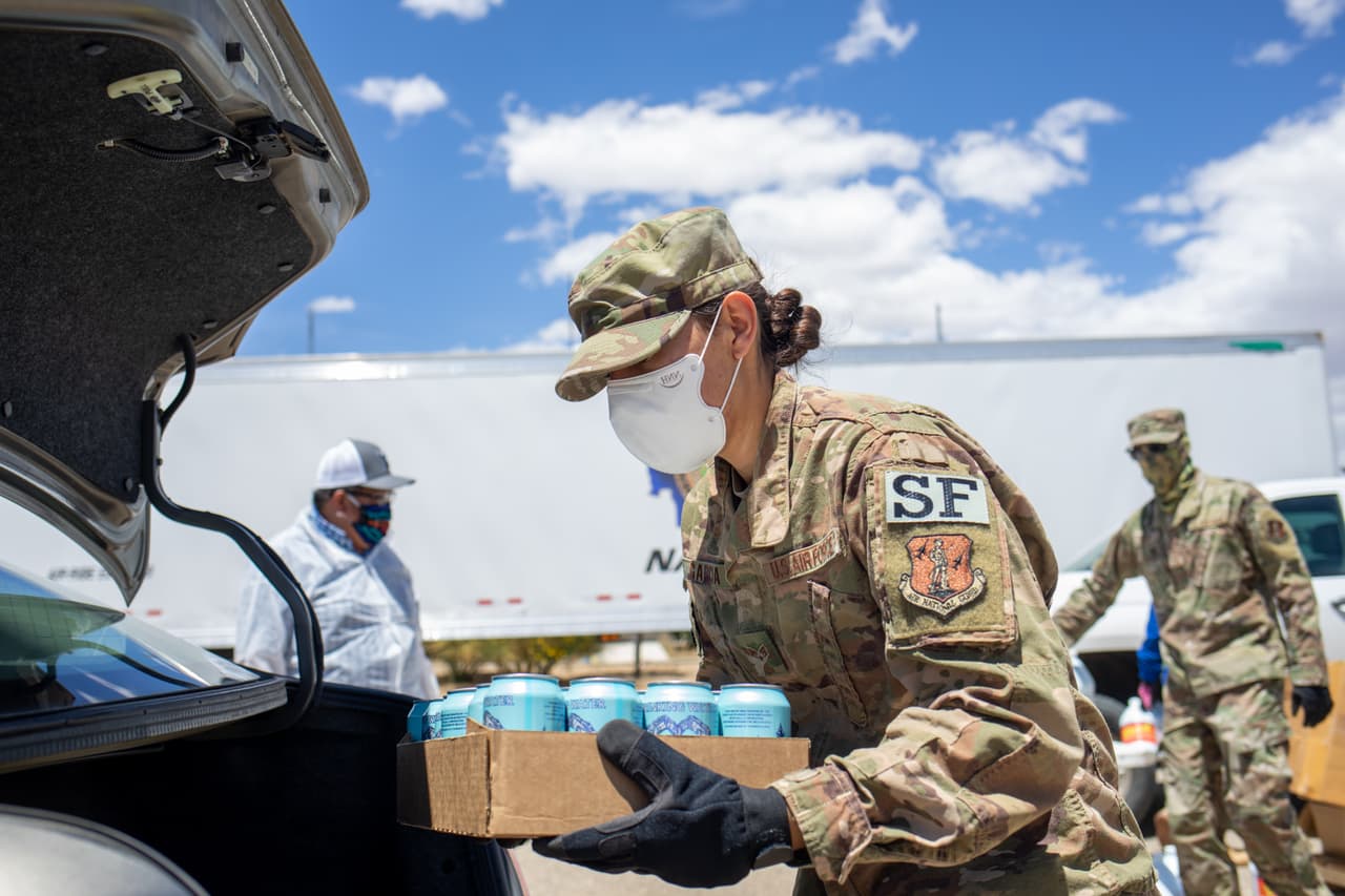 El presidente tribal Jonathan Nez firmó una orden que extiende el cierre de las oficinas y entidades del gobierno tribal hasta el 5 de julio. En la foto se observa a Selena García, miembro de la Fuerza Aérea carga alimentos y suministros en el automóvil de una familia el 27 de mayo de 2020 en Huerfano, en la Reserva de Nación Navajo, Nuevo México. La Nación Navajo abarca partes de Utah, Arizona y Nuevo México y tiene el mayor número de casos positivos de Covid-19 per cápita en los Estados Unidos, ya que la propagación del coronavirus continúa afectando desproporcionadamente a las comunidades minoritarias en todo el país.
