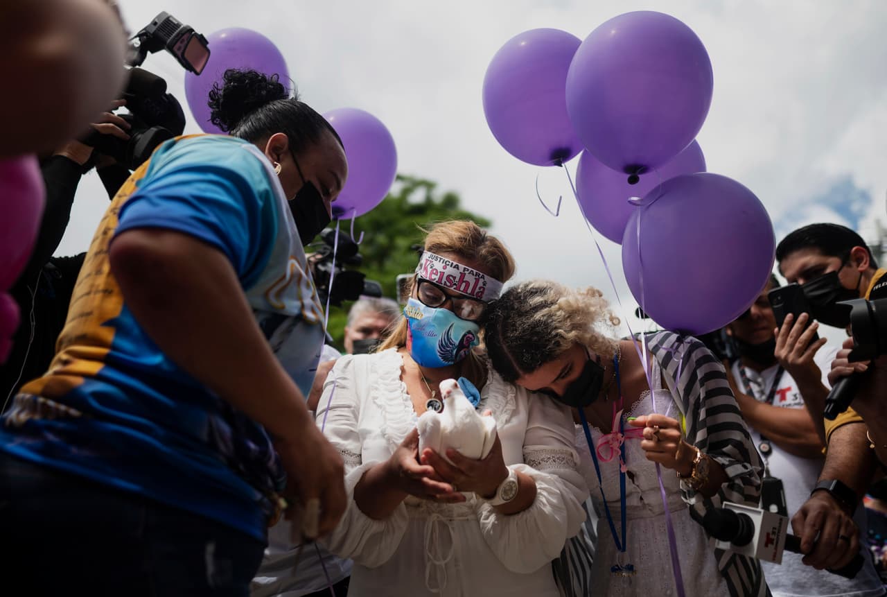 Bereliz Rodríguez se apoya en el hombro de su madre Keila Ortiz, quien sostiene una paloma para ser liberada en memoria de su hija asesinada Keishla Rodríguez.