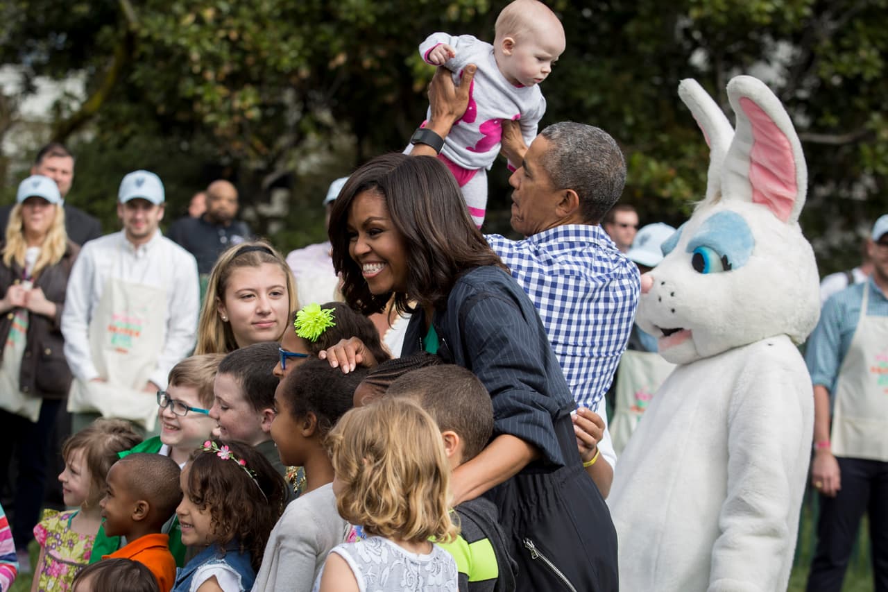 La primera dama Michelle Obama posa para una foto con un grupo de niños mientras Obama carga a un bebé