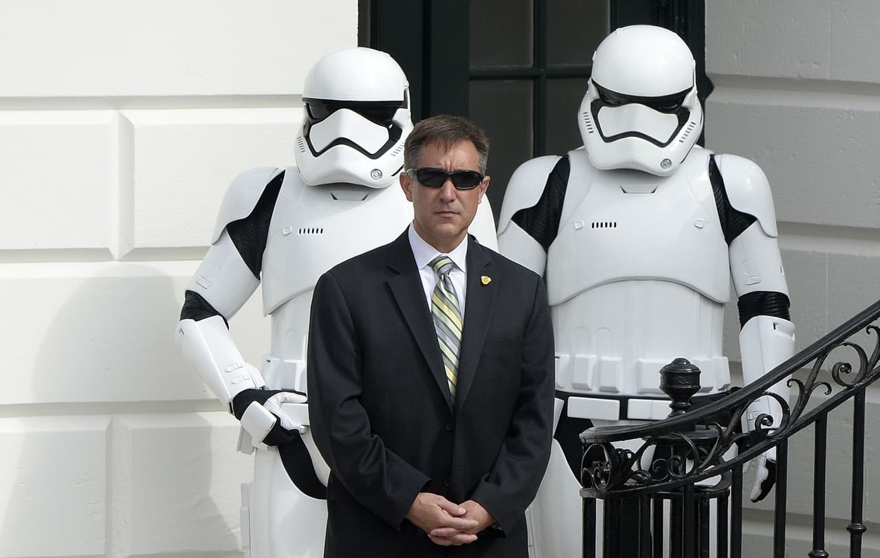 Un agente del servicio secreto se detiene frente a dos personas disfrazadas de "Stormtroopers", personajes de la película Star Wars