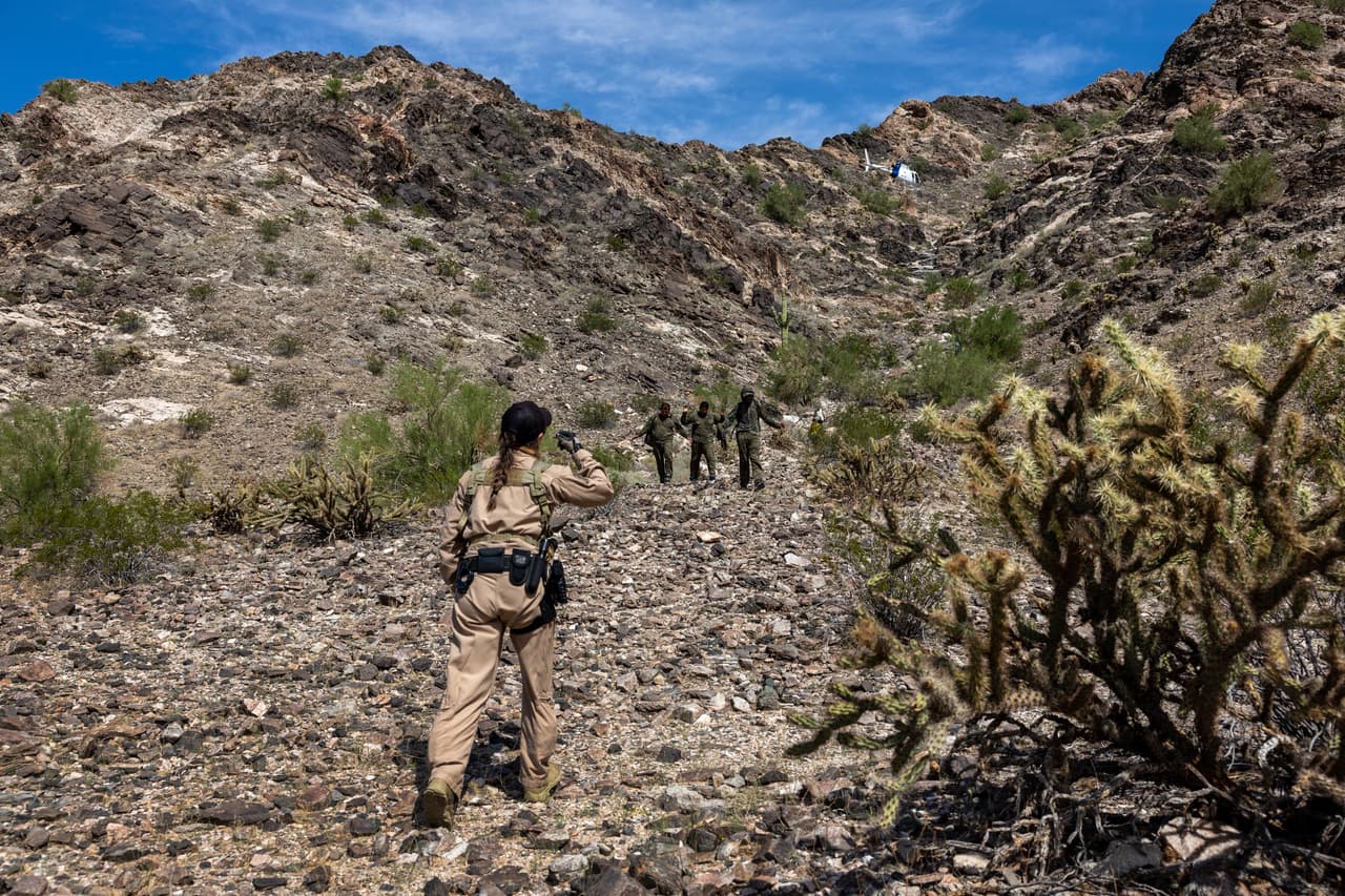 Un agente de Aduanas y Protección Fronteriza detiene a un grupo de inmigrantes después de rastrearlos a través de un terreno accidentado en el Monumento Nacional Organ Pipe, en Arizona.