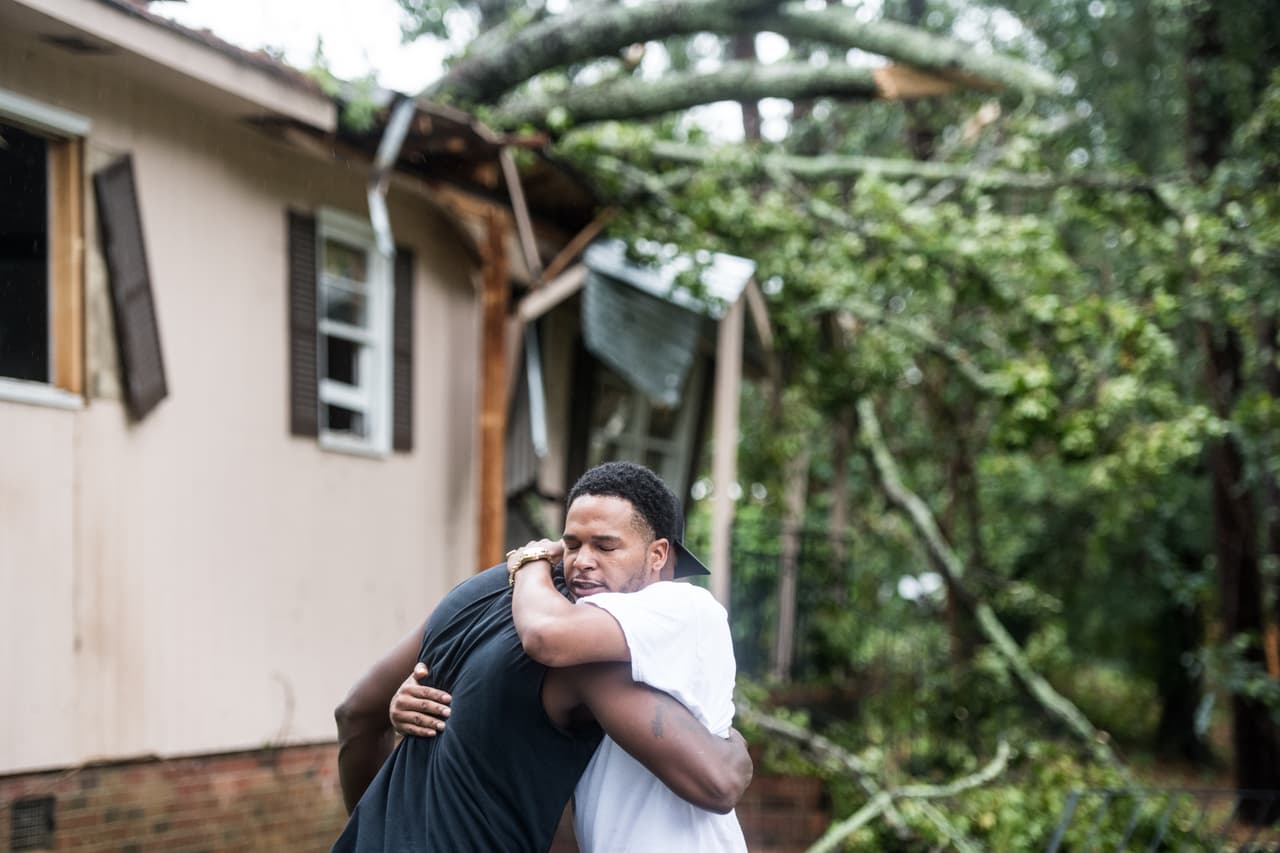 Héctor Benthall, a la derecha, recibe un abrazo de su vecino Keito Jordan después de que los vientos del huracán Michael lanzaron un árbol sobre la casa de Benthall en Columbia, Carolina del Sur. Jordan fue el primero en responder al accidente que envió al menos a una persona al hospital.