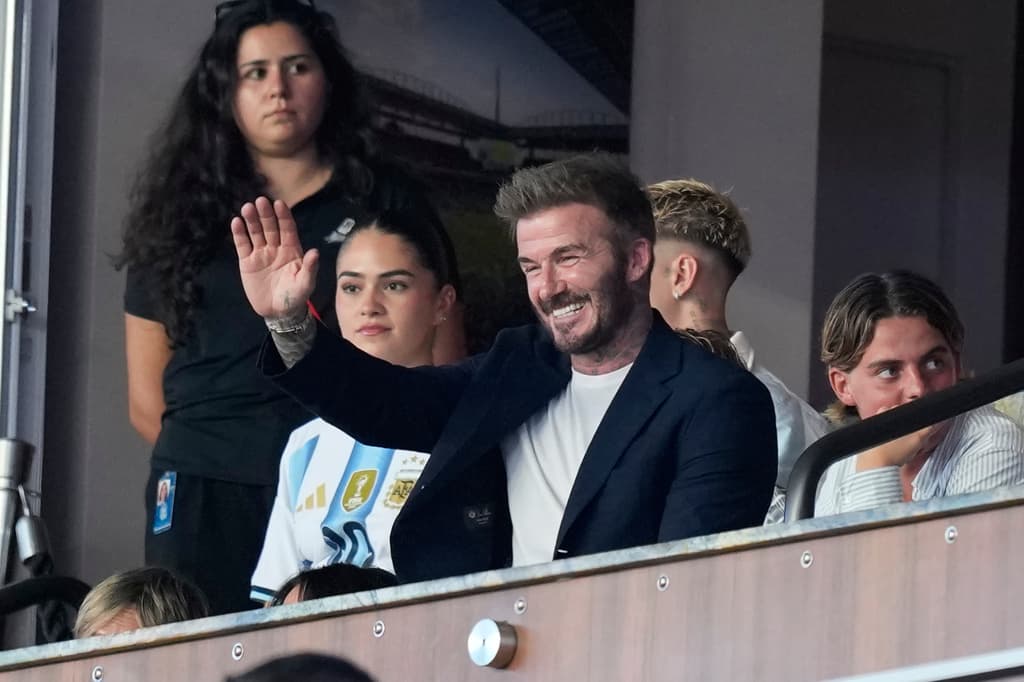La leyenda del futbol inglés David Beckham saluda desde la tribuna a los aficionados.