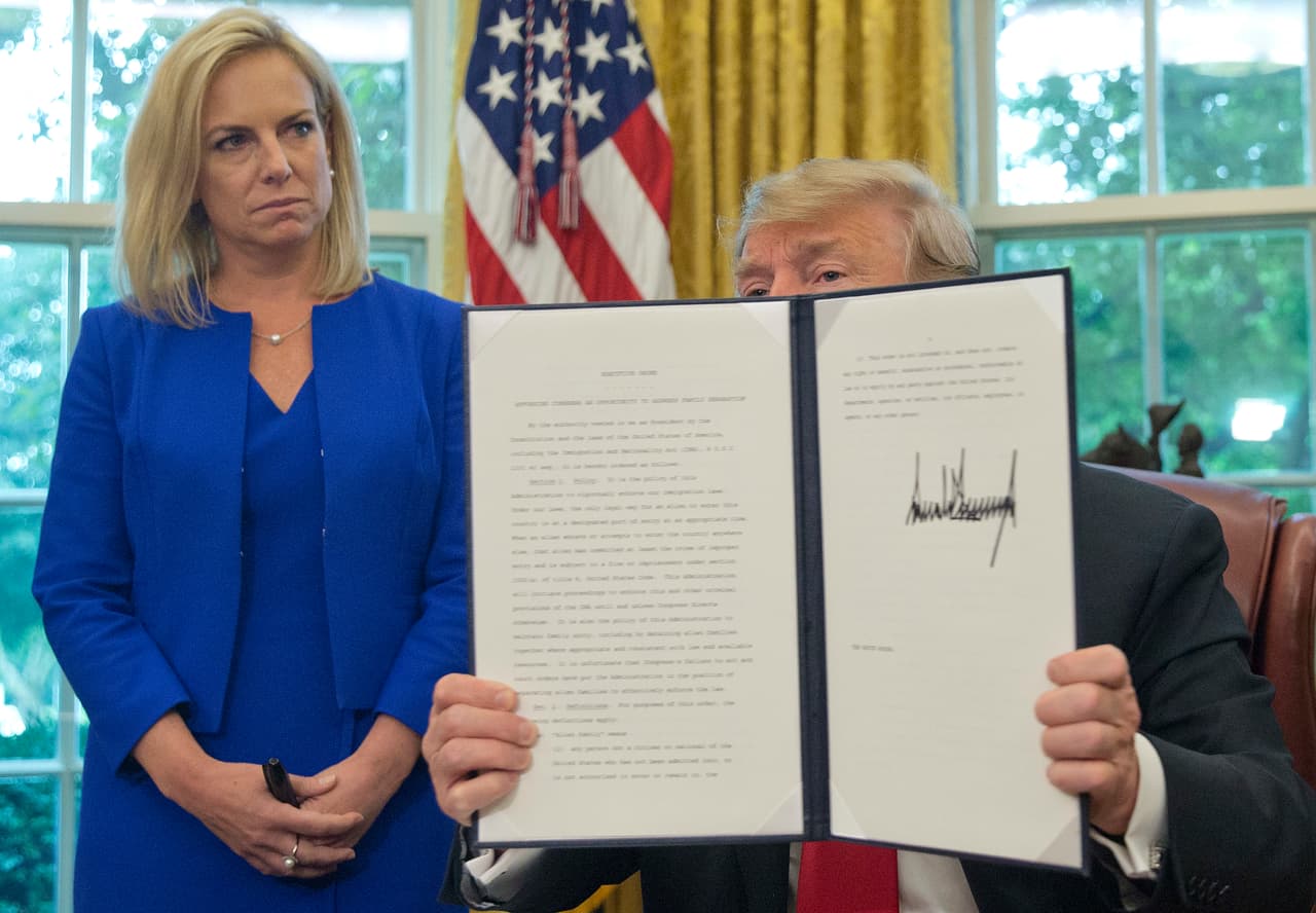 Donald Trump firmó la orden en un breve acto realizado en la Oficina Oval de la Casa Blanca el 20 de junio de 2018, flanqueado por el vicepresidente Mike Pence y la secretaria de Seguridad Nacional, Kirstjen Nielsen. Intenta resolver la crisis migratoria que creó su propio gobierno a principios de mayo al establecer la llamada 'cero tolerancia'.