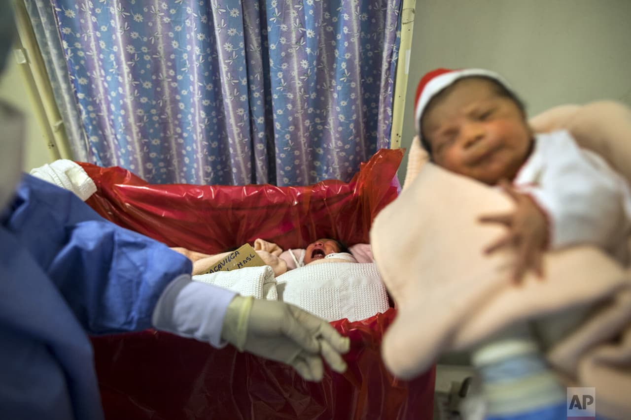 Un bebé recién nacido 
<b>llora acostado en una cuna forrada con una lámina de plástico roja</b> para identificar a los bebés cuyas madres están infectadas.
