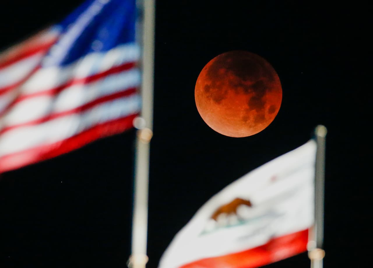 La luna se vistió de rojo esta madrugada. Así se observó entre las banderas de EEUU y California en la playa de Santa Mónica.