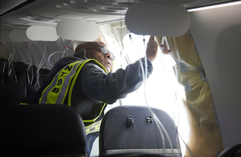 En esta fotografía publicada por la Junta Nacional de Seguridad en el Transporte, el investigador a cargo de la NTSB, John Lovell, examina el área del tapón del fuselaje desprendido en el vuelo 1282 de Alaska Airlines.