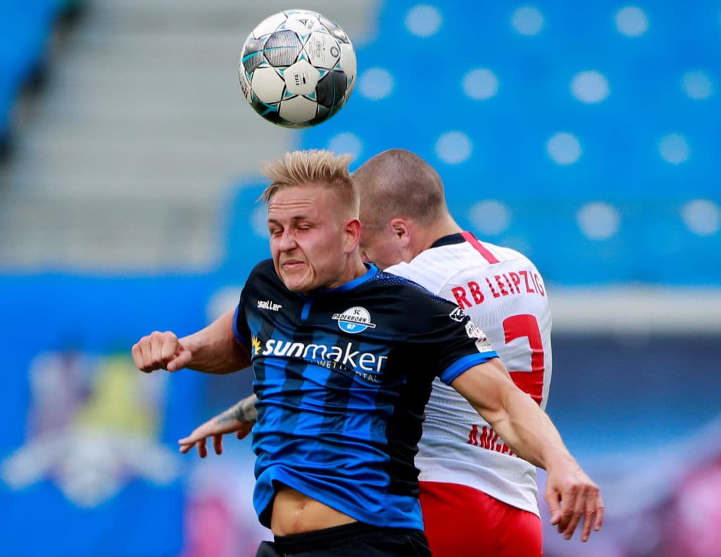 Kai Proger y el defensor español Angelino se levantan para tratar de ganar el eférico luego del despeje de área de Leopold Zingerle.