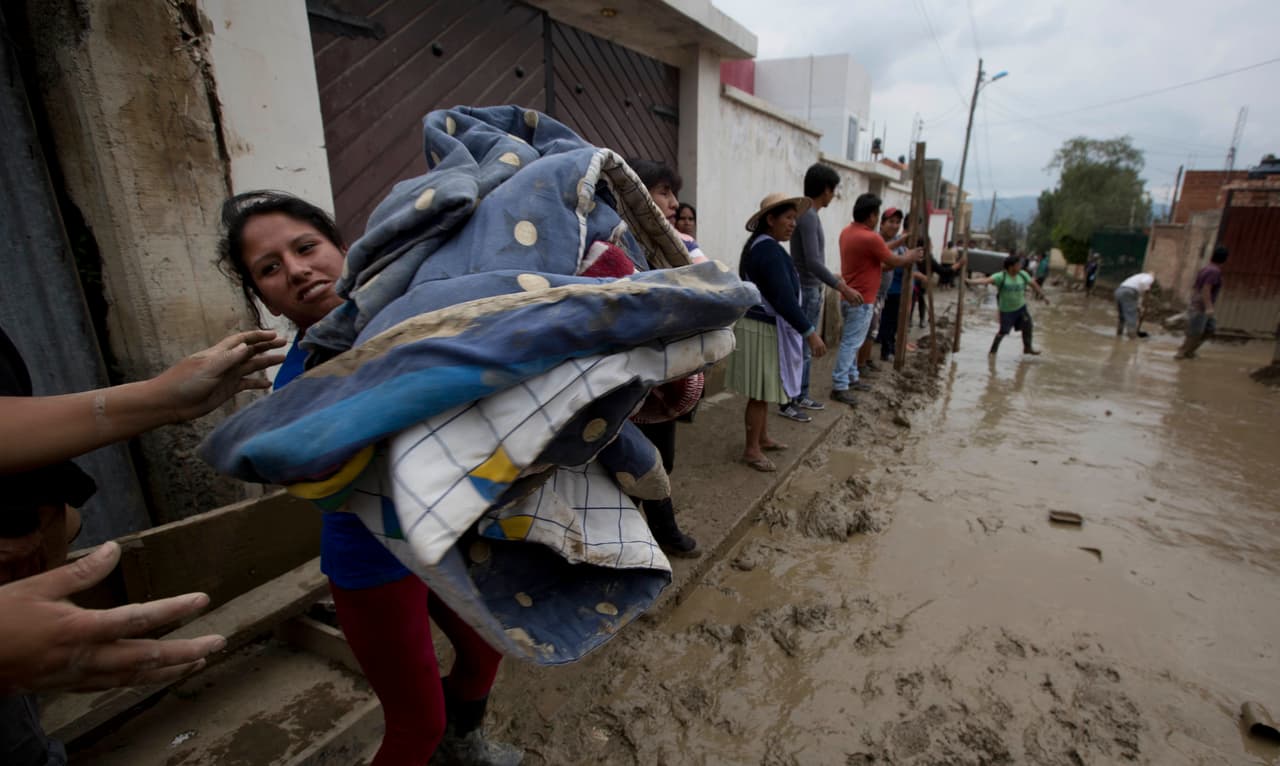 Las autoridades enviaron maquinaria pesada al lugar para tratar de controlar el cauce del río y habilitaron albergues para las familias afectadas. En la foto, residentes de Cochabamba se agrupan para rescatar sus pertenencias de las casas tapiadas de lodo.