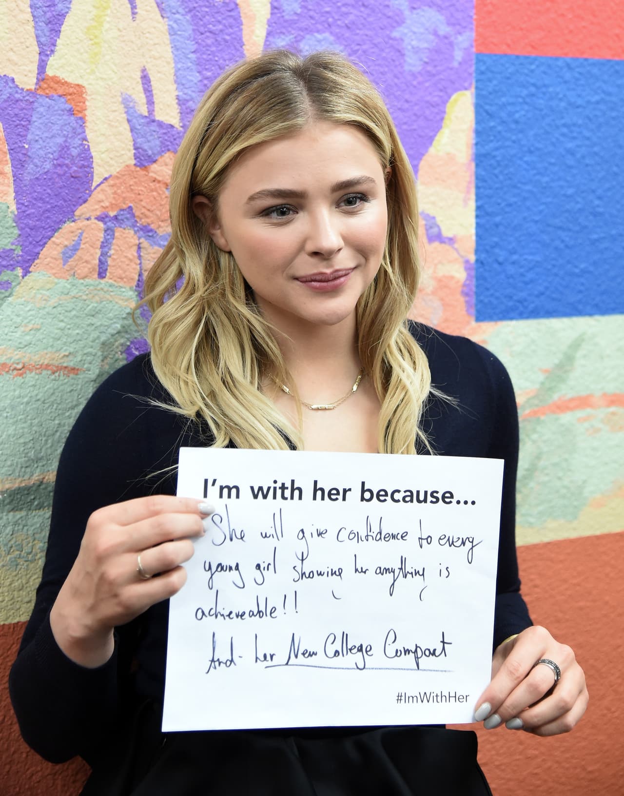 Con un letrero que muestra por qué votará por ella.