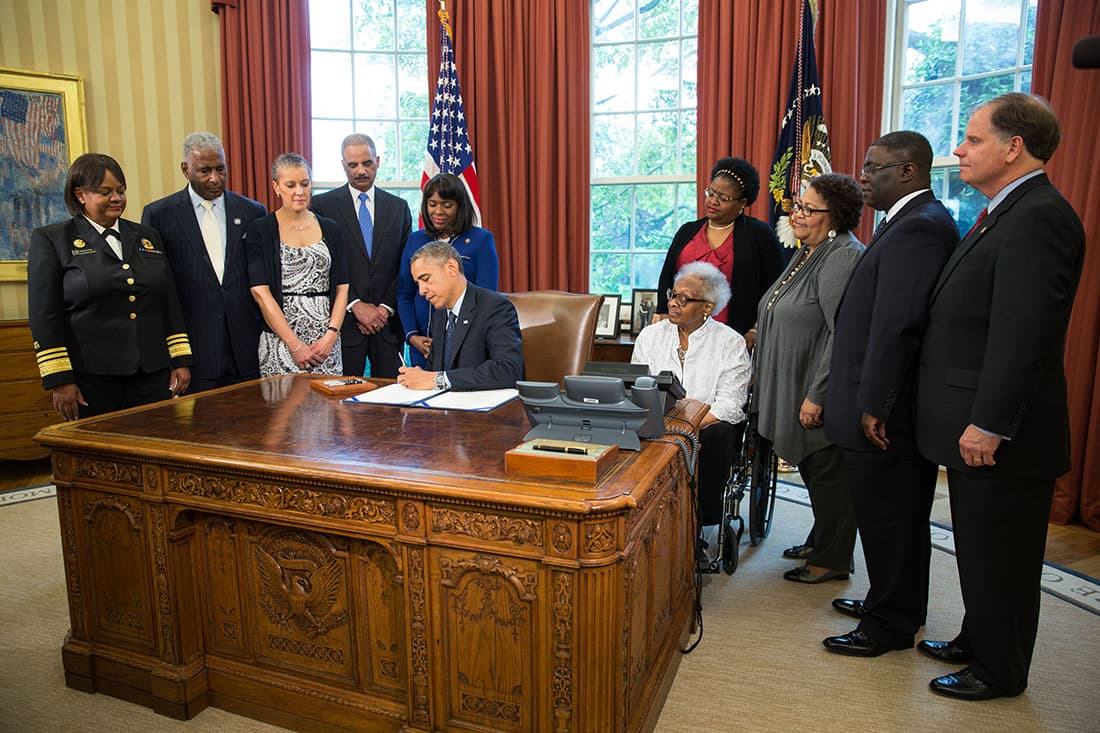 President Barack Obama signs a bill in the Oval Office designating the Congressional Gold Medal to commemorate the four young girls killed during the 1963 bombing of 16th Street Baptist Church in Birmingham, Alabama, by white supremacists. Former US Attorney Doug Jones is on the far right along with (L-R) Surgeon General Regina Benjamin, Birmingham Mayor William Bell, Dr Sharon Malone Holder, Attorney General Eric Holder, Rep Terri Sewell (D-AL), Thelma Pippen McNair, mother of Denise McNair, Lisa McNair, sister of Denise McNair, Dianne Braddock, sister of Carole Robertson, Rev Arthur Price, Jr, pastor 16th Street Baptist Church. May 24, 2013 in Washington, DC.