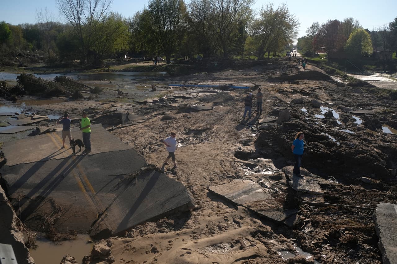Los habitantes de la zona exploran lo que quedó del puente de West Curtis, arrastrado por las aguas.
