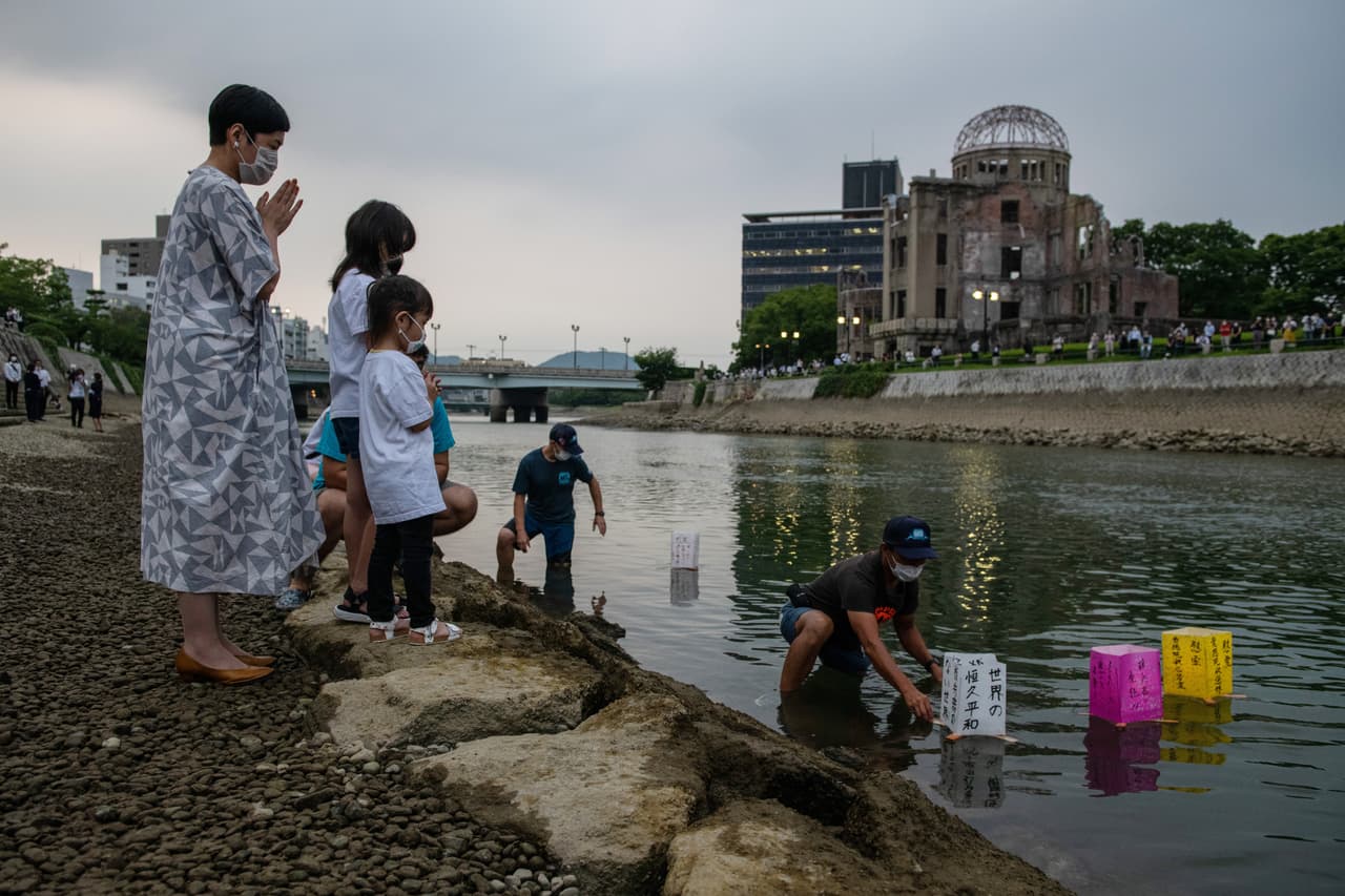 Una familia coloca linternas de papel sobre el río Tenma el 6 de agosto de 2020, para conmemorar el 75 aniversario del bombardeo.
<br>
<br>Esta es una tradición que cada año se realiza en la ciudad japonesa. Al fondo el 'Domo de la bomba atómica'.