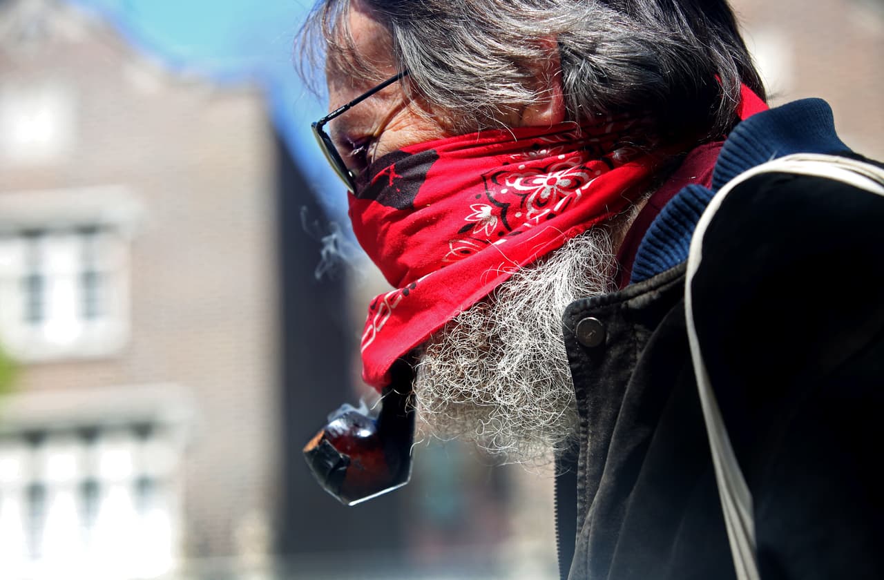 Tom Bonnett, de Brooklyn, fuma una pipa debajo de su máscara mientras camina por Prospect Park durante el agradable clima del fin de semana, ya que las pautas de distanciamiento social siguen vigentes para limitar la propagación del coronavirus.
