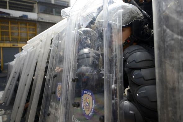 Los policías se escudan mientras los motorizados disparan a mansalva, asesinando a dos estudiantes y a un oficial. Los estudiantes llevaron a cabo una manifestación pacífica contra el régimen del mandatario Nicolás Maduro el 12 de febrero de 2014. Motorizados uniformados y con sus caras cubiertas, dispararon contra los manifestantes, matando a dos estudiantes y a un oficial.