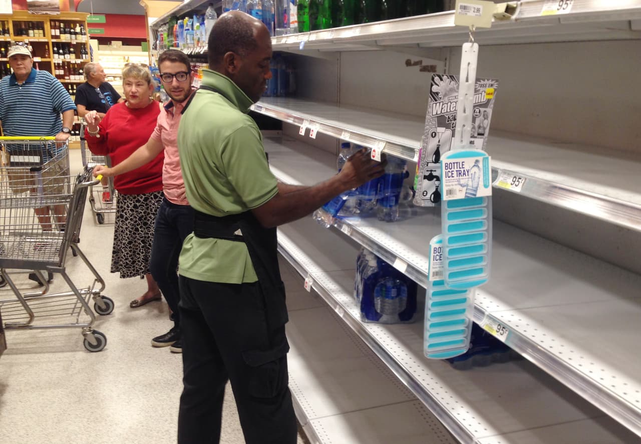 Un empleado de la tienda Publix en Surfside, reabastece un anaquel de agua, recién agotado por las compras nerviosas.